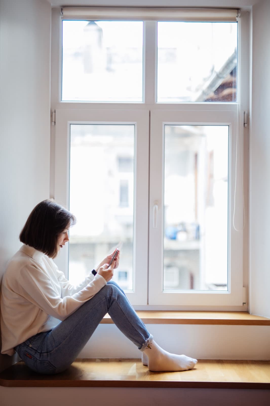 Woman sitting on a windowsill beside a white uPVC tilt-and-turn window